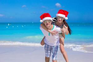 giovane contento coppia nel rosso Santa cappelli su bianca spiaggia foto