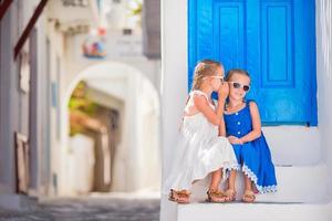 poco ragazze a strada di tipico greco tradizionale villaggio su mykonos isola, nel Grecia foto