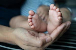 mani delle madri che tengono i piedi del bambino foto