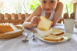 primo piano di un ragazzo che immerge un pezzo di pane tostato foto