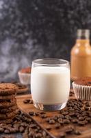 latte in un bicchiere con chicchi di caffè e muffin