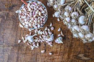 aglio e spicchi d'aglio in una ciotola su uno sfondo di legno foto