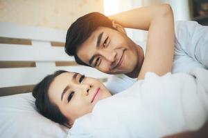 coppia felice posa insieme nel loro letto foto