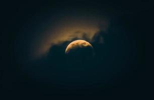 luna di notte parzialmente coperta dalla nuvola. luna piena con nuvole drammatiche nel cielo notturno.