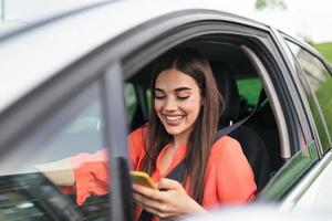 giovane ragazza usi un' mobile Telefono nel il macchina. tecnologia cellula Telefono isolamento. Internet e sociale media. donna con smartphone nel sua macchina. ragazza è utilizzando un' smartphone foto