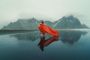 donna nel salutò rosso vestito su reynisfjara spiaggia panoramico fotografia foto