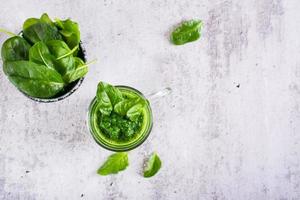 fresco spinaci frullato nel un' bicchiere e un' ciotola con le foglie su il tavolo. naturale antiossidante. superiore Visualizza foto