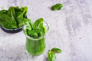 verde spinaci frullato nel un' bicchiere su un' grigio sfondo. salutare cibo. foto