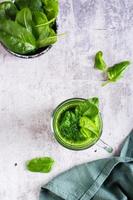 verde spinaci frullato nel un' bicchiere su un' grigio sfondo. salutare cibo. superiore e verticale Visualizza foto