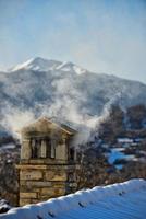 un' montagna Casa tetto con fumo camino foto