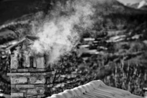 un' nero e bianca montagna Casa tetto con fumo camino foto