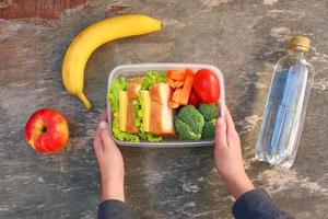 panini, frutta e verdure nel cibo scatola, acqua su vecchio di legno sfondo. superiore Visualizza. piatto posizione. foto