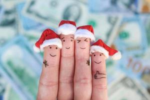 dita arte di amici celebra Natale su il sfondo di i soldi. il concetto di un' gruppo di persone ridendo nel nuovo anno cappelli. foto