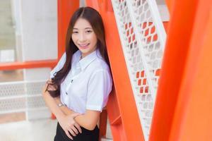 ritratto di un adulto tailandese alunno nel Università alunno uniforme. asiatico carino ragazza in piedi sorridente felicemente dove sua denti siamo indossare fermi guardare a telecamera con fiducia per presente qualche cosa. foto