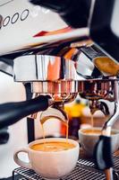 caffè estrazione a partire dal il caffè macchina con un' portafilter scrosciante caffè in un' tazza, espresso poro a partire dal caffè macchina a caffè negozio foto