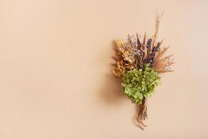 un' mazzo di asciutto fiori e erbe aromatiche su beige sfondo. copia spazio per testo foto