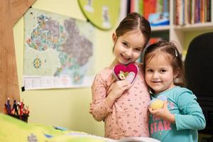 Due poco ragazze sorelle mostrare cuore Ucraina bandiera nel camera. supporto ucraino. foto