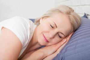bella maturo donna addormentato con occhi chiuso nel il letto foto