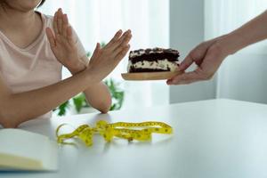 magro donne rifiuto per mangiare cioccolato torta. donne fare non mangiare trans grassi e zucchero. dieta concetto foto