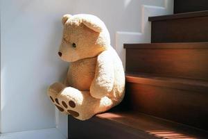 bambino concetto di tristezza. orsacchiotto orso seduta pendente contro il parete di il Casa solo, Guarda triste e deluso. foto