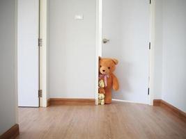 dentro casa. il orsacchiotto orso famiglia ha aperto il porta dietro a il parete e sbirciato Alcuni. foto
