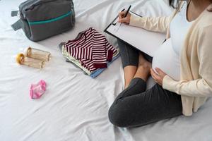 incinta donne siamo contento per preparare bambino Abiti. Imballaggio borse per andando per il ospedale foto