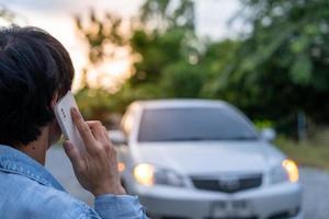 sicurezza di emergenza. l'uomo sta componendo un telefono cellulare per un numero di emergenza a causa di un guasto a un'auto nella foresta. la manutenzione dell'auto prima del viaggio aumenta la sicurezza dagli incidenti. foto