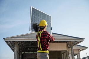 tecnici trasporto solare pannelli pronto per essere installato su il tetto di un' alloggiamento tenuta Risparmio energetico e riduzione dei costi concetto proprio un' piccolo attività commerciale installazione solare pannelli. foto