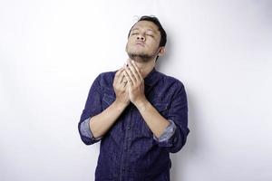 ragazzo asiatico bello spirituale calmo che prega con gli occhi chiusi. giovane serio e pacifico con le mani unite che meditano. concetto di credenza foto