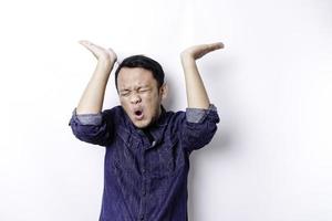 scioccato asiatico uomo indossare blu camicia puntamento a il copia spazio su superiore di lui, isolato di bianca sfondo foto