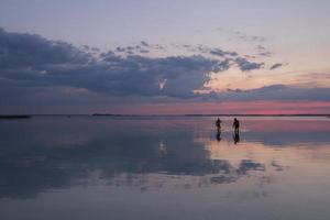 spensierato persone nuoto nel lago a tramonto paesaggio foto