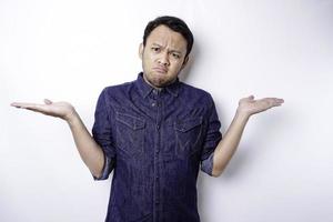 un' ritratto di un asiatico uomo indossare un' blu camicia sembra così confuso fra scelte, isolato di un' bianca sfondo foto