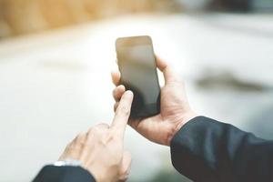 il turista giovane uomo viaggiatore con zaino In piedi in attesa pubblico auto Guarda a il lui mano uso il Telefono per dai un'occhiata il programma per partire viaggio a il stazione.viaggio concetto. foto