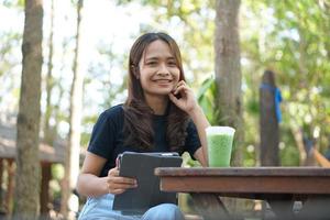 asiatico donne siamo contento per sedersi e opera nel un' caffè negozio. Là siamo verde alberi circondato di natura. attività commerciale pianificazione è un' bene idea. foto