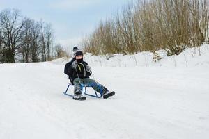 contento piccolo ragazzo nel inverno neve coperto cortile foto