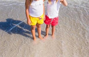 adorabile poco ragazze avere divertimento nel superficiale acqua a tropicale spiaggia foto