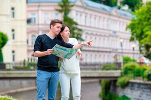 giovane turista coppia in viaggio su vacanze nel Europa. caucasico famiglia con città carta geografica nel ricerca di attrazioni foto
