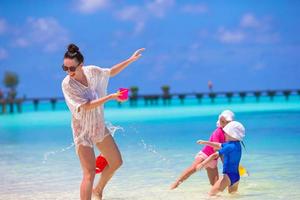 giovane mamma e poco ragazze avendo divertimento durante estate spiaggia vacanza foto