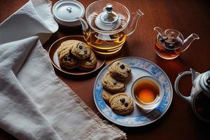 fotografia di un' piatto di biscotti e un' bicchiere di tè su un' tavolo con un' stoffa e un' tovagliolo su esso foto