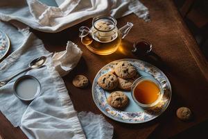 fotografia di un' piatto di biscotti e un' bicchiere di tè su un' tavolo con un' stoffa e un' tovagliolo su esso foto