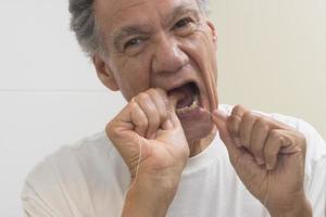 anziano uomo filo interdentale il suo denti con dentale filo foto