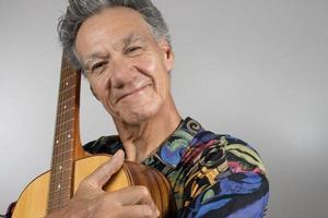 anziano uomo indossare un' colorato camicia Tenere il suo acustico chitarra foto