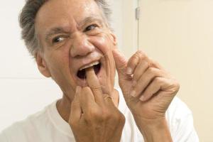 anziano uomo filo interdentale il suo denti con dentale filo foto