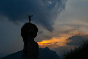 uomo conquista il superiore di un' montagna dopo un' difficile scalata foto