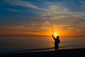 pescatore su il riva di il mare sistema il pesca asta foto