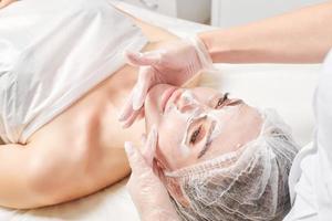 cosmetologo massaggi crema maschera in donna viso pelle per ringiovanimento, procedura nel bellezza salone foto