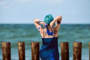 artista di performance artistica donna dai capelli blu in abito imbrattato con pitture a guazzo blu sul suo corpo foto