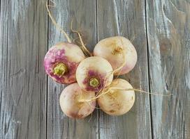 fresco viola rapa impilati su di legno grigio sfondo foto