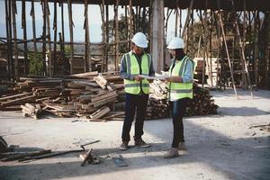 Due specialisti ispezionare commerciale, industriale edificio costruzione luogo. vero tenuta progetto con civile ingegnere, progettazione commerciale edifici su carta. grattacielo calcestruzzo cassaforma cornici. foto