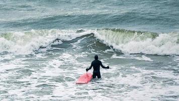 surfista maschio in costume da bagno in mare con tavola da surf rossa foto